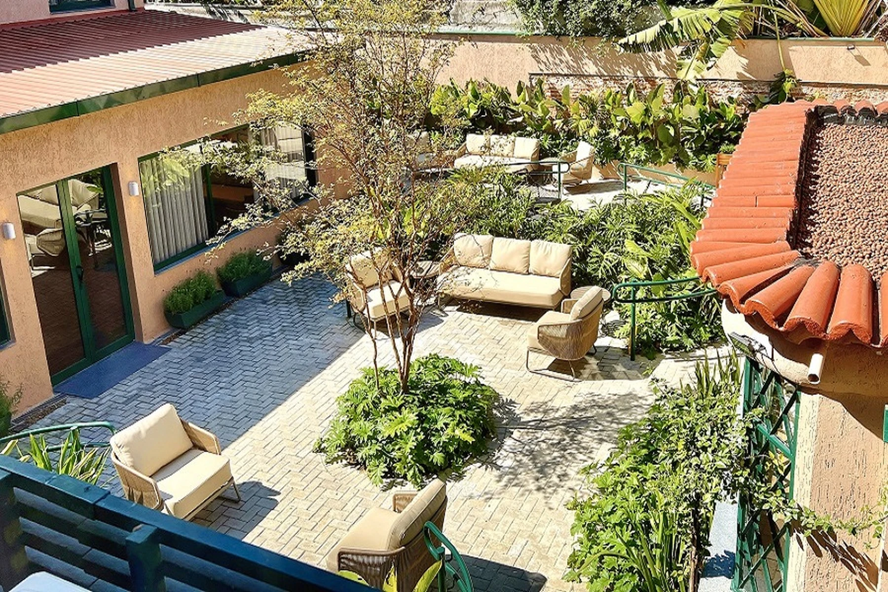 Um ambiente externo ou jardim com mesas e bancos de madeira e vegetação, criando um espaço de lazer ao ar livre.