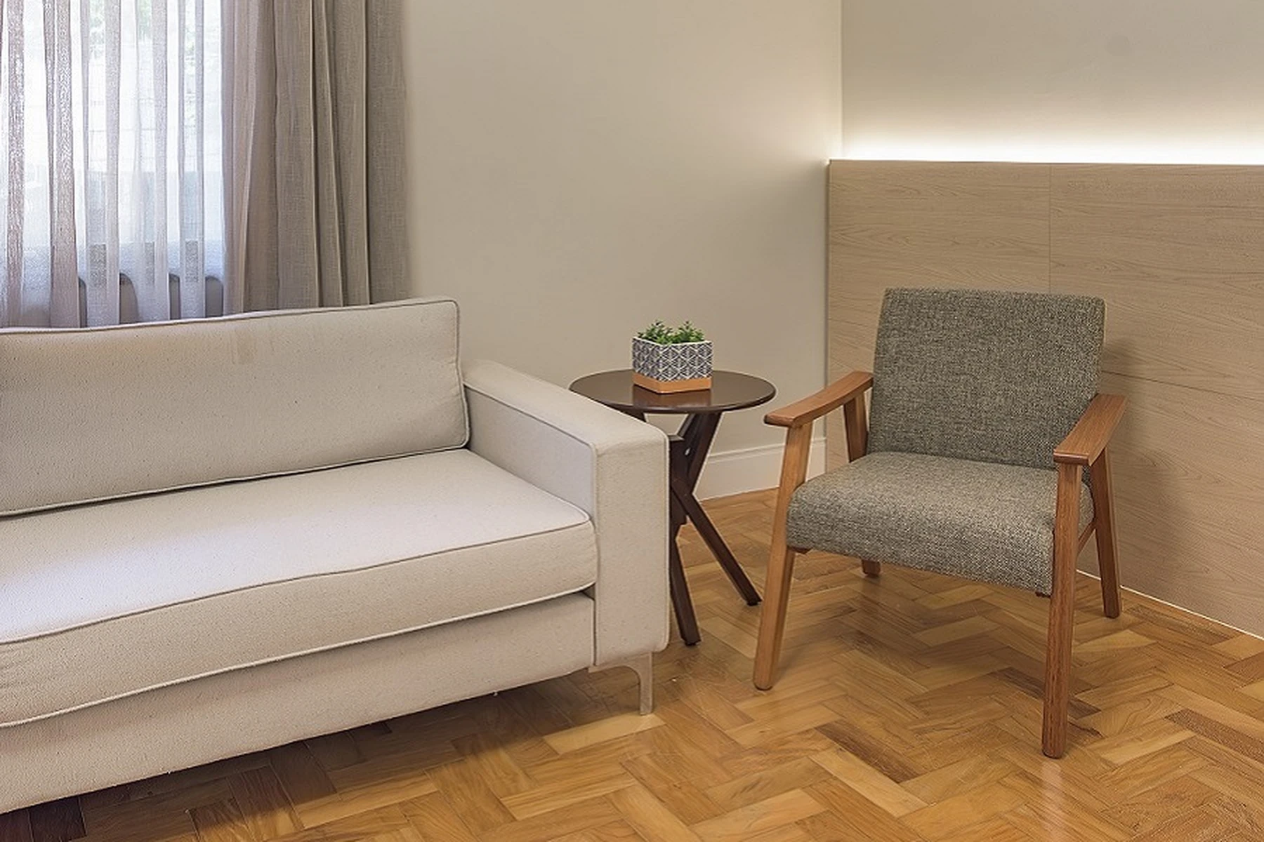 Um quarto de casa de repouso com cama de solteiro, criado-mudo e luminária, mostrando um ambiente limpo e acolhedor.
